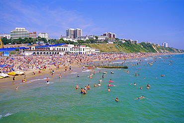 Holidaymakers in the sea and on the beach, Bournemouth, Dorset, England, UK