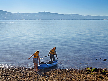 Couple launching kayak, Matiu/Somes Island in Wellington Harbour, North Island, New Zealand, Pacific