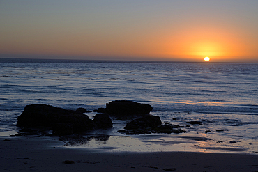 Sunset over the ocean, with rocks in the foreground, San Simeon, California, United States of America, North America