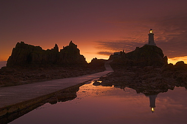 Dramatic sunset, low tide, Corbiere lighthouse, St. Ouens, Jersey, Channel Islands, United Kingdom, Europe