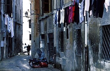 Italy, Rome, Trastevere, Popular Small Street With Drying Laundry And Bikes Remains