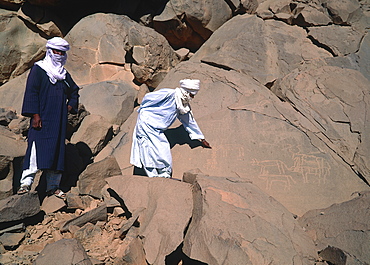 Algeria, Sahara, Hoggar, Tuaregs On A Rocky Slope Pointing At Prehistoric Drawings 