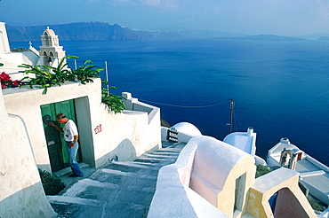 Greece, Cyclades, Santorini Island, Man Knocking A Green Door At A House In Ia Village Overlooking The Sea  