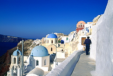 Greece, Cyclades, Santorini Island, Ia Village Small Path, White Painted Houses And Chapel Domes On Left, Man Returning With Bread