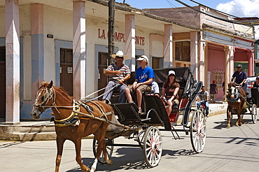 Tourists enjoying a horse-drawn buggy ride through Moron, Ciego de Cvila, Cuba, West Indies, Central America