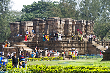 Pilgrims among ruins in the grounds of the mid 13th century Sun Temple, dedicated to Surya, the Hindu Sun God, constructed as a twelve-wheeled chariot drawn by seven horses, UNESCO World Heritage Site, Konarak, Puri District, Odisha, India, Asia