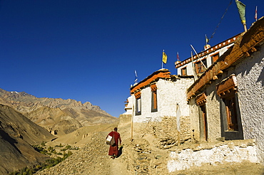 Monk walking past Lamayuru gompa (monastery), Lamayuru, Ladakh, Indian Himalayas, India, Asia