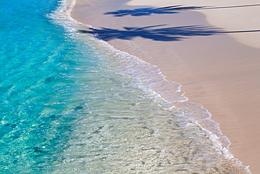 The crystal clear water of the Indian Ocean with a deserted beach and the shadow of two palm trees, The Maldives, Indian Ocean, Asia