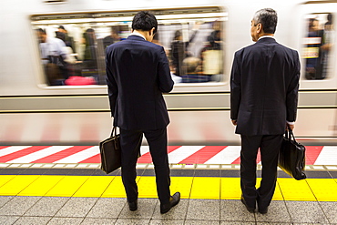 Two businessmen waiting for a train on the Tokyo Metro, Tokyo, Japan, Asia