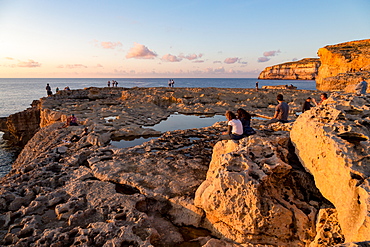 People enjoying sunset at Dwejra Bay on the rugged Gozo coast, Malta, Mediterranean, Europe