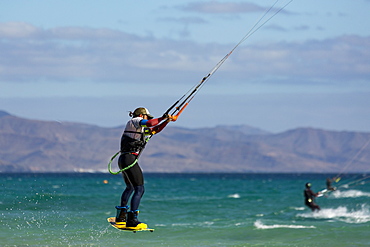 Man jumping whilst kiteboarding off the Playa de La Barca, Costa Calma, on the volcanic island of Fuerteventura, Canary Islands, Spain, Atlantic, Europe