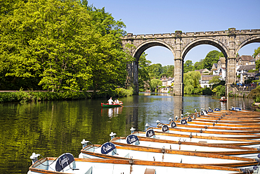 People rowing past boats for hire in front of the Railway Viaduct over the river Nidd in Knaresborogh In the county of Yorkshire.