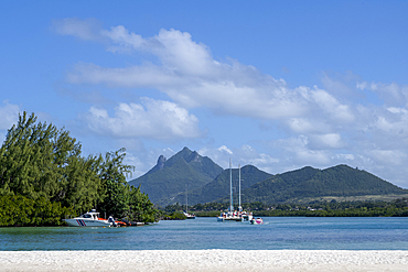 Catamaran yachts and a moored coast-guard boat, with the dramatic Bambous Mountain in the distance, on the exotic island of Mauritius in the Indian Ocean