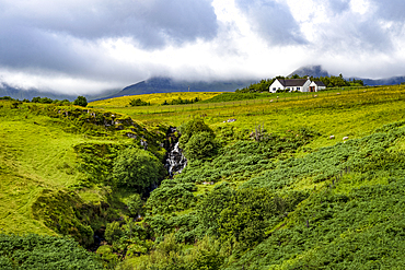 Lone cottage and waterfall near Staffin on the Isle of Skye, Inner Hebrides, Scotland.