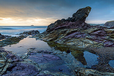 Purple coloured rocks on the Cornish shoreline at sunset, Polzeath, Cornwall, England, United Kingdom, Europe