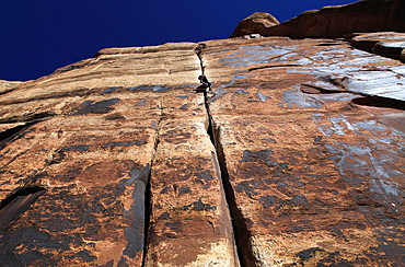 A rock climber tackles an overhanging crack in a sandstone wall on the cliffs of Indian Creek, a famous rock climbing area in Canyonlands National Park, near Moab, Utah, United States of America, North America