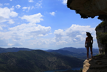 A woman looks out across the hills of Catalonia from a rock ledge near the village of Siuarana, near Reus and Barcelona, Catalonia, Spain, Europe