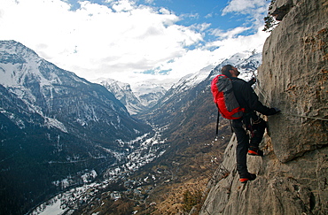 A man on a via ferrata route high above the tiny village of Fressinieres, near Briancon, Ecrins Massif, western Alps, France, Europe