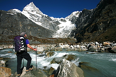 A trekker pauses for a break on the edge of a glacial stream on the way to Mera Peak, a popular trekking peak in the Khumbu Region, near Mount Everest, Nepal, Himalayas, Asia