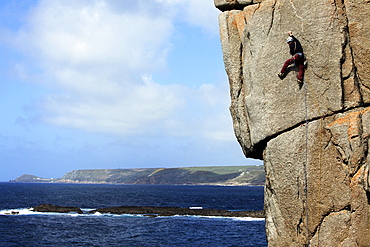 A climber scales cliffs at Sennen Cove, Cornwall, England, United Kingdom, Europe