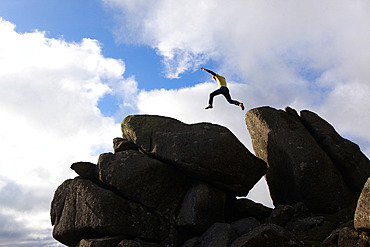 A parkour athlete jumping between boulders on Dartmoor, Devon, England, United Kingdom, Europe