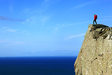 A hiker looks out to sea from cliffs at Fair Head, County Antrim, Ulster, Northern Ireland, Europe