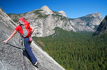 A rock climber ascends slabs at the base of the huge cliff known as The Apron, overlooking Washington Column and North Dome, Yosemite Valley, California, United States of America, North America