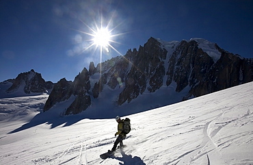 A snowboarder enjoys superb spring snow high on the famous Valley Blanche ski run, one of the world's most celebrated glacier descents, with Mont Blanc Du Tacul in the distance, Mont Blanc, Chamonix, western Alps, France, Europe