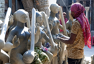 Sculptor adding hands to goddess Durga deities, made of Hooghly river clay over straw base in Kumartuli potters quarter, Kolkata (Calcutta), West Bengal, India, Asia