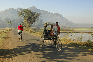 Early morning rickshaw wallahs pass each other in rural countryside near Baliguda, Orissa, India