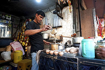 Chai wallah, pouring Indian chai into traditional hand made terracotta clay cups, in chai stall outside Kali temple, Kolkata (Calcutta), West Bengal, India, Asia