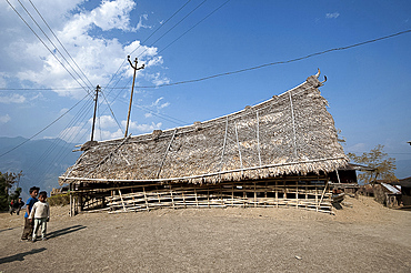 Naga children beside small bamboo constructed, fan palm thatched murung (meeting hall) with traditional curved roof, Nagaland, India, Asia