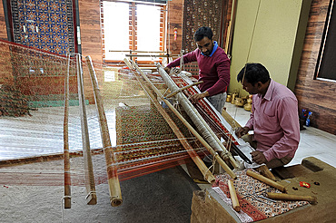 Two men working together to weave a complex double ikat Patola sari using a harness loom slanted to one side, Patan, Gujarat, India, Asia