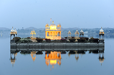 Vijay Raj Rajeshwar temple, reflected in the Gaibsagar Lake, built in 1923, lighting up at dusk for evening prayers, Dungarpur, Rajasthan, India, Asia