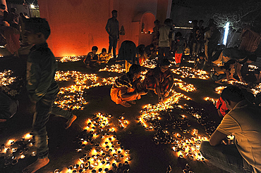 Hindu devotees placing lit puja lamps in temple courtyard to celebrate annual festival of Shivraatri, Koraput district, Odisha, India, Asia