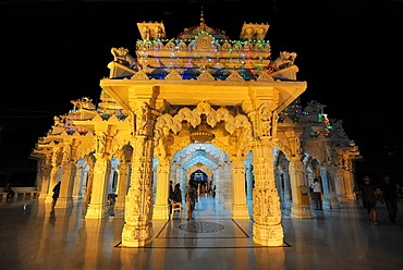 Entrance to the beautiful white marble Swaminarayan Temple, illuminated for evening prayers, Mandvi, Gujarat, India, Asia