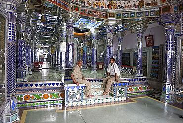 Two men sitting in ornately decorated Jain temple in backstreet, Udaipur, Rajasthan, India, Asia