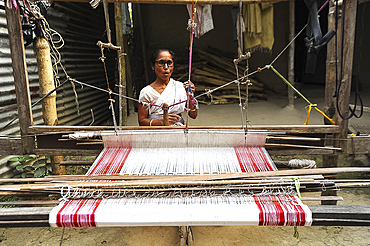 Village woman with domestic handloom, weaving a traditional Assamese cotton gamosa, white with red borders, Assam, India, Asia