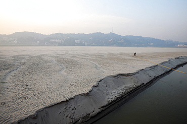 Pre-dawn cast off, man releasing ropes from a mooring in the fine sand of a seasonal sandspit in the Brahmaputra River, Assam, India, Asia