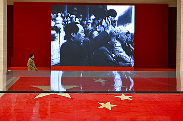 Museum visitor walking past party political slideshow in the National Museum of China, Beijing, China, Asia