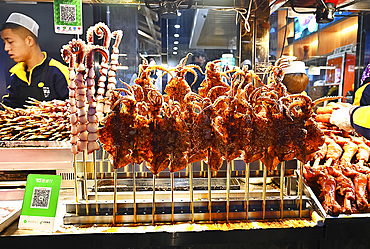 Fried squid on sticks and octupus tentacles in street market in Muslim quarter, Xian, Shaanxi, China, Asia