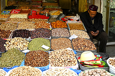 Uyghur Muslim stallholder selling locally grown and dried fruit and nuts, Kashgar, Xinjiang, China, Asia