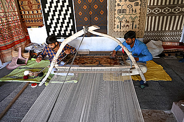 Two men weaving patterned wool carpet on a hand built traditional wooden loom, Bhuj, Gujarat, India, Asia