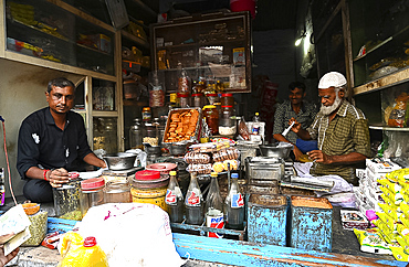 Village general stores, Muslim shopkeeper measuring honey for a customer, Dasada village, Gujarat, India, Asia