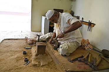 Muslim bell maker beating copper into shape to make bells by hand for cattle or for the home, Nirona village, Gujarat, India, Asia