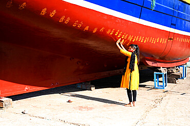 Daughter of boat owner performs puja on new boat by making hand prints along its hull prior to maiden launch, Vanakbara, Gujarat, India, Asia