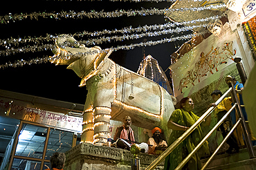 Saddhus sit under decorative marble elephant at the entrance to the Jagdish temple at Diwali, Udaipur, Rajasthan, India, Asia