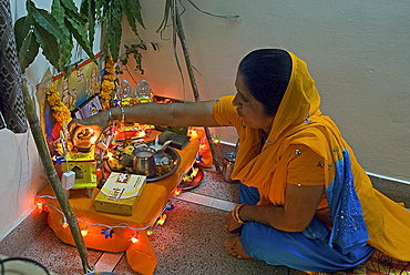 Sikh woman placing deepak light on domestic Diwali shrine, Jaipur, Rajasthan, India, Asia