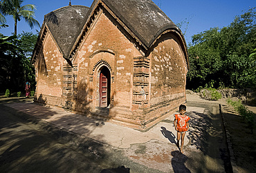 Young village girl beside restored miniature terracotta Hindu temple to Shiva, Baranagar, rural West Bengal, India, Asia