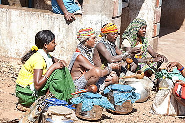 Bonda tribeswomen wearing traditional beaded caps and metal necklaces, selling village-made alcohol at weekly market, Rayagader, Orissa, India, Asia